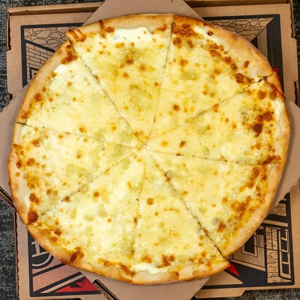 A whole Massimo’s Beachside Pizza cheese pizza, cut into slices, in a cardboard box.