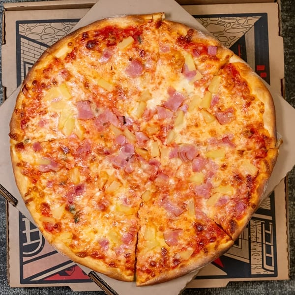 Massimo’s Beachside Pizza's Hawaiian pizza, topped with ham and pineapple, in a pizza box.