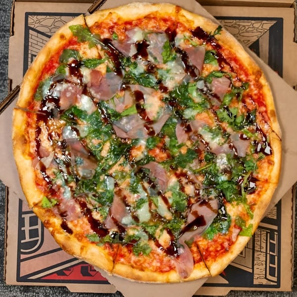 Massimo's Beachside Pizza with prosciutto, arugula, mozzarella, and balsamic glaze in a pizza box.