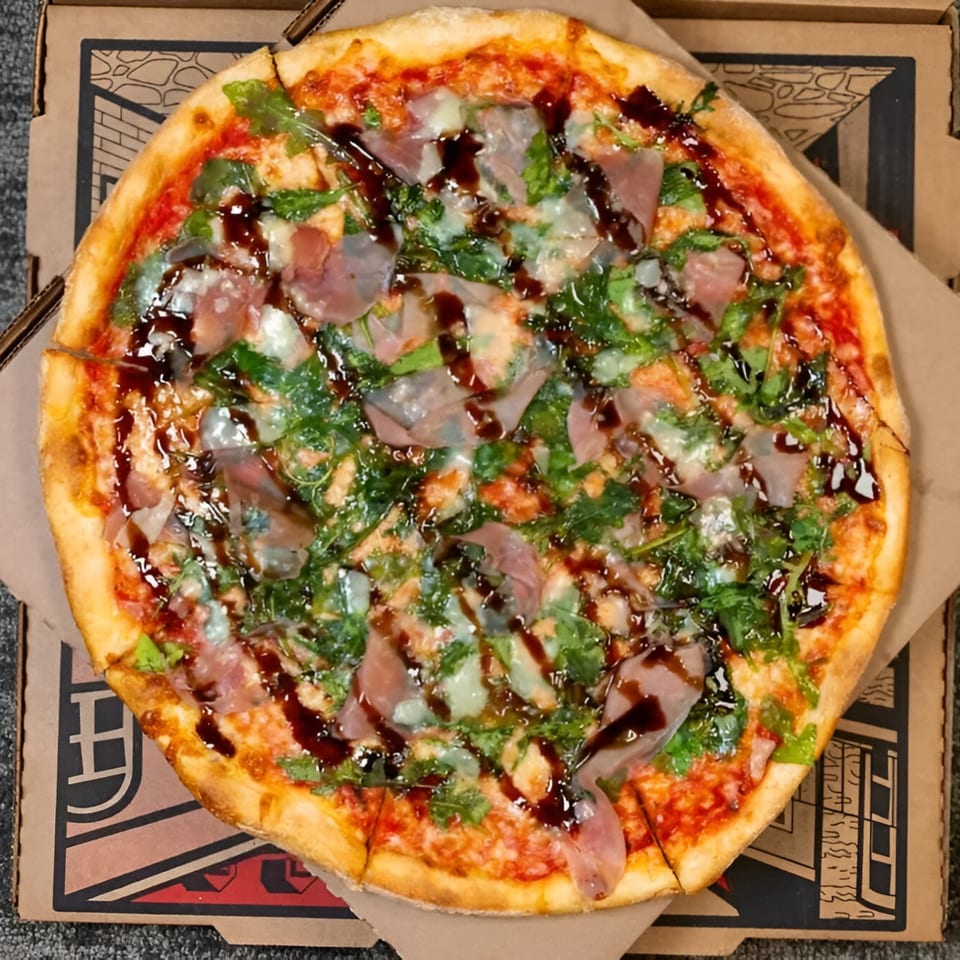 Massimo's Beachside Pizza with prosciutto, arugula, mozzarella, and balsamic glaze in a pizza box.