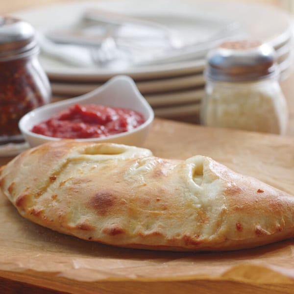 Massimo’s Beachside Pizza calzone with a side of marinara sauce, red pepper flakes, and parmesan cheese.